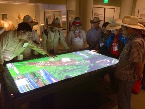 A crowd of bridge builders visiting NMAI from Peru navigate the 3D model
